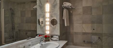 Un baño moderno con dos lavamanos, un espejo grande, una ducha con cerramiento de vidrio y un perchero para toallas.