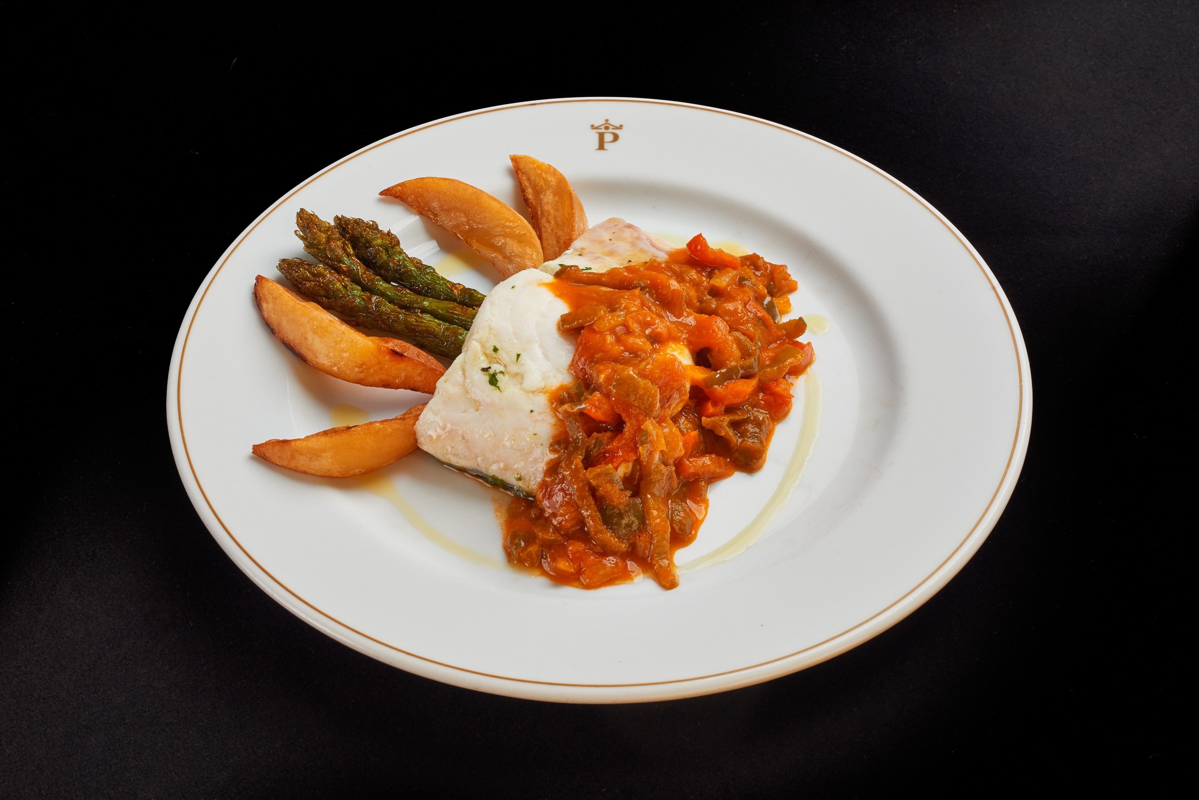 A plate with a piece of fish, roasted vegetables, and a tomato-based sauce.
