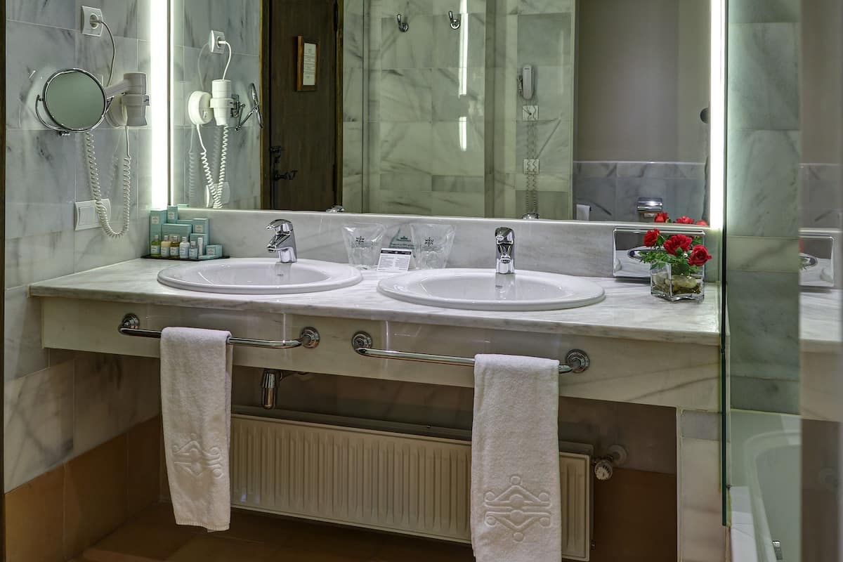 A modern bathroom with two sinks, a large mirror, and a glass shower enclosure.