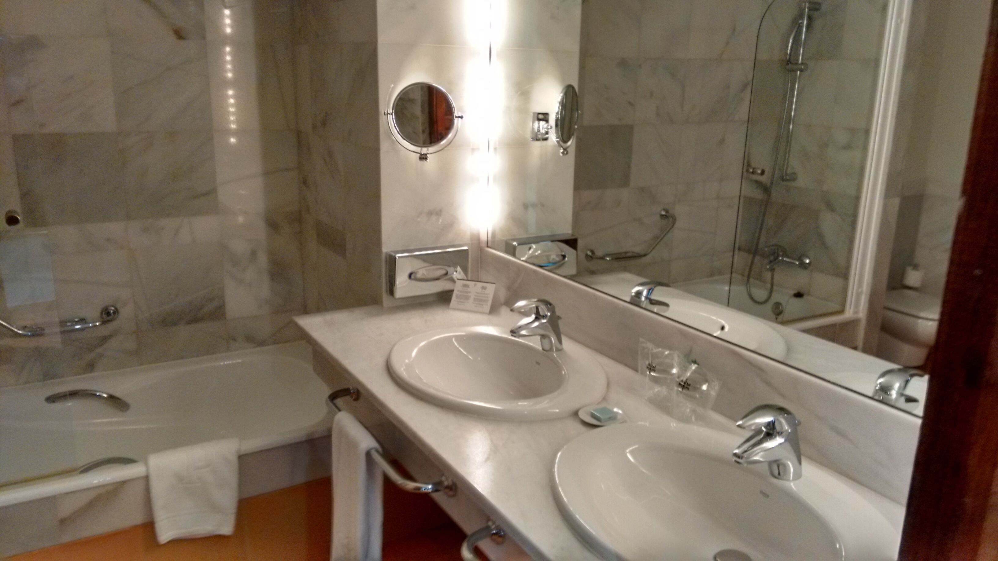 Un baño con dos lavamanos, una ducha y un espejo grande.