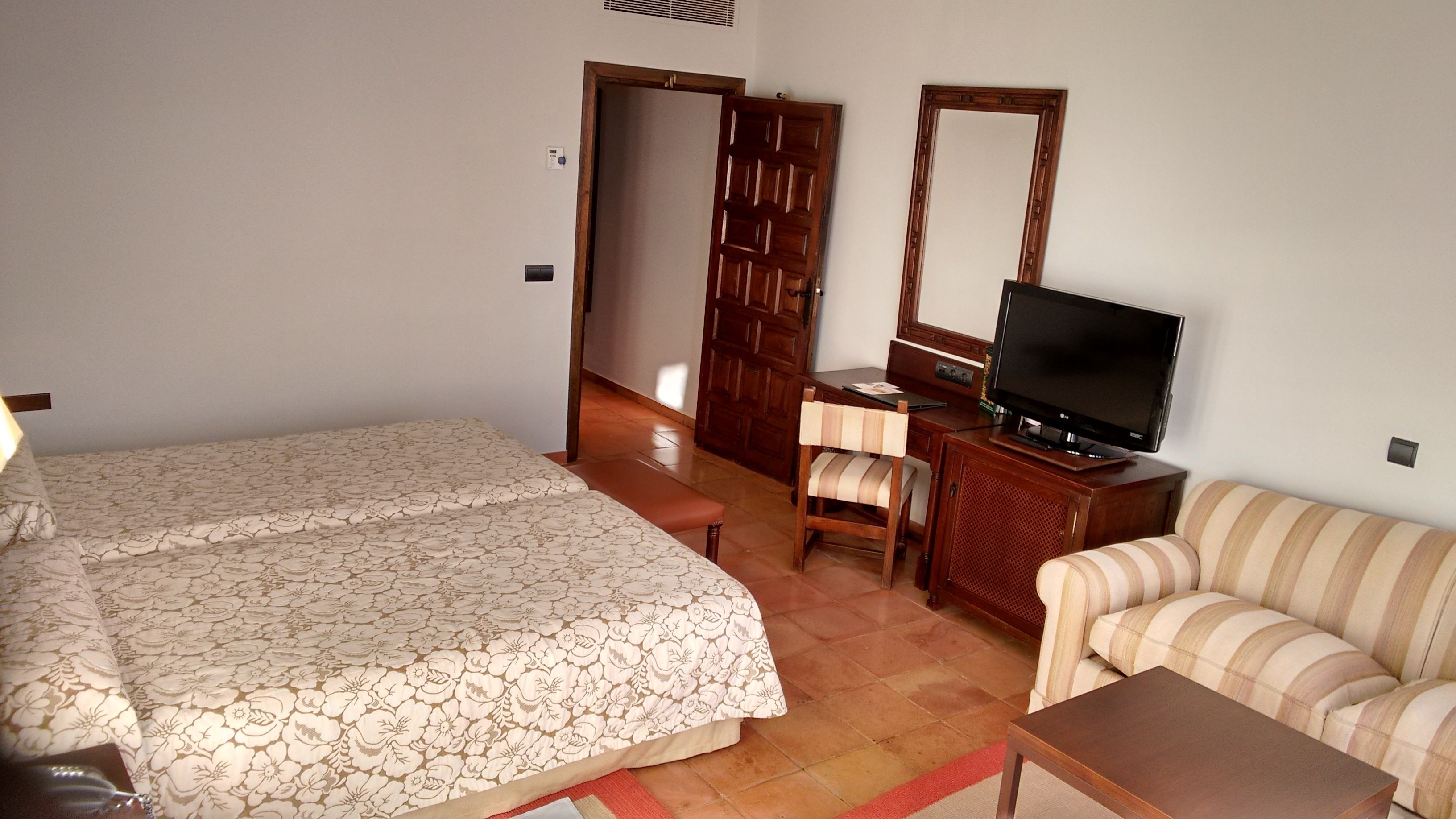 A hotel room with a bed, a sofa, a television, a desk, and a chair.