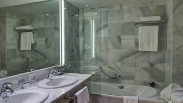 A modern bathroom with two sinks, a glass-enclosed shower, and a bathtub.