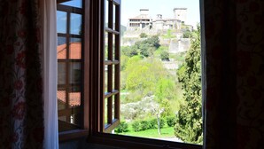 A room with a large window offering a view of a historic building and lush greenery.