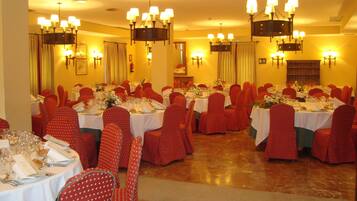 Un comedor formal con varias mesas dispuestas para el servicio, sillas rojas y candelabros.
