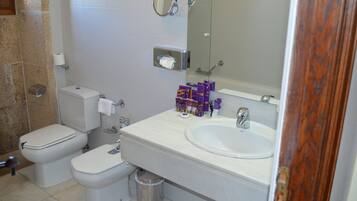 Un baño con dos inodoros, un lavabo, un espejo y artículos de aseo en la encimera.