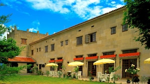 A courtyard with outdoor seating and a stone building with multiple windows and awnings.