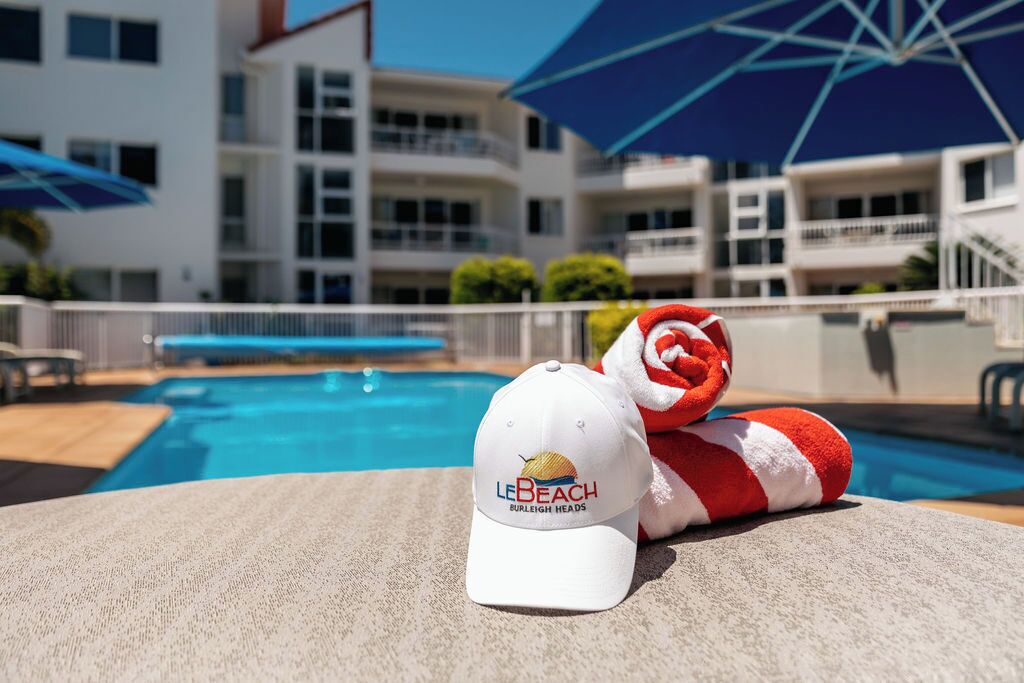 Uma área ao lado da piscina, com um chapéu branco e uma toalha vermelha e branca.