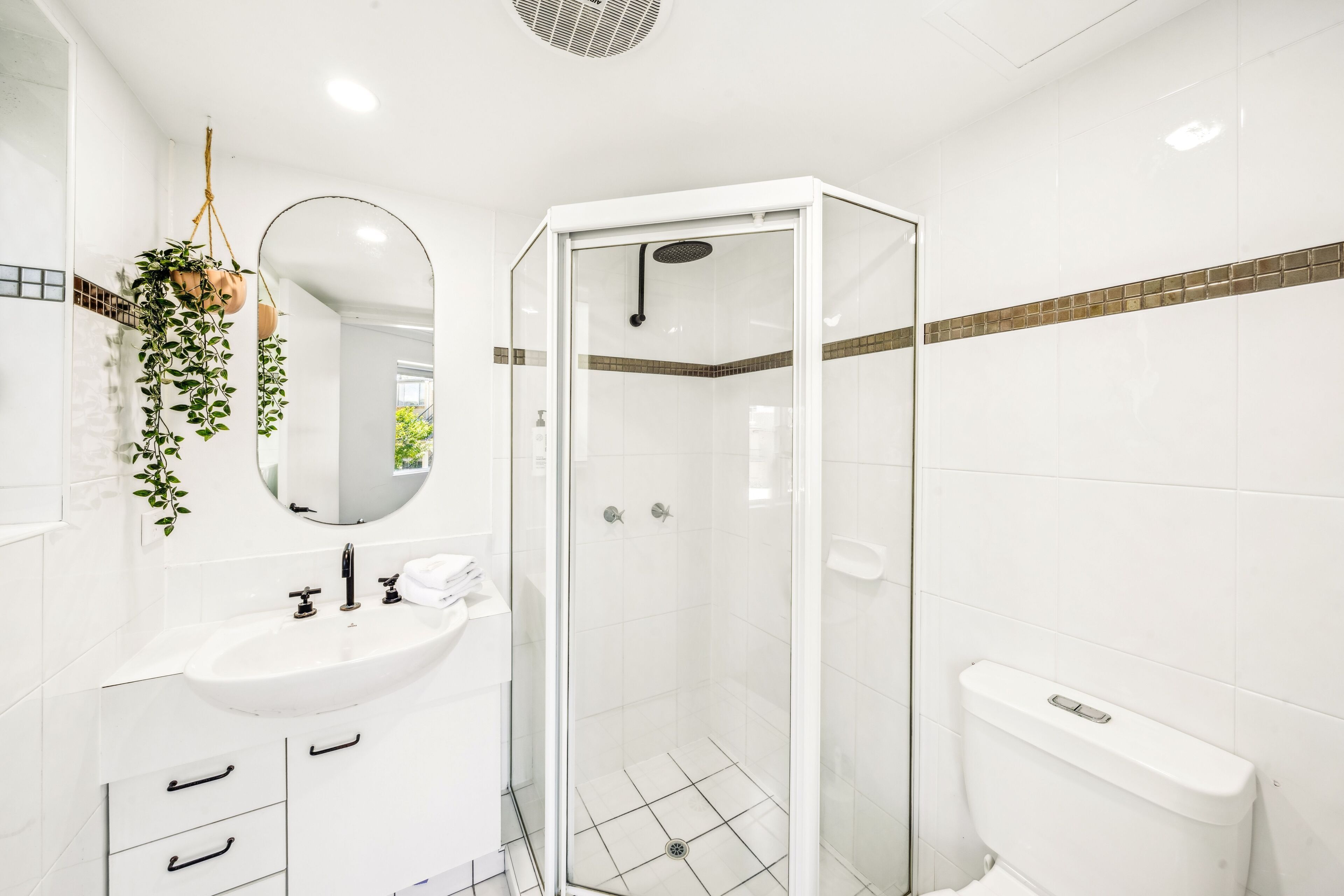 Un bany modern amb dutxa de vidre, un lavabo blanc i un mirall.