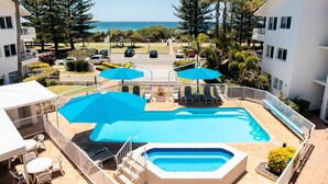 A pool area with a hot tub, umbrellas, and lounge chairs. - Le Beach Apartments (Burleigh Heads)