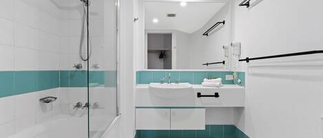 Ein modernes Badezimmer mit einer Duschkabine, einem weißen Waschbecken mit blauen Akzenten und einem Spiegel darüber.