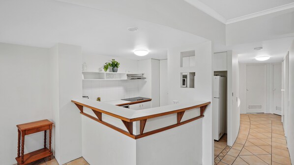 Una cocina moderna con armarios blancos, encimera de madera y microondas integrado.