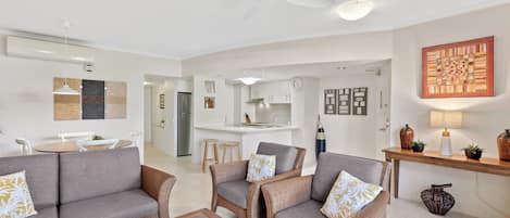 A modern living room with a sofa set, a coffee table, and a dining area with a table and chairs.