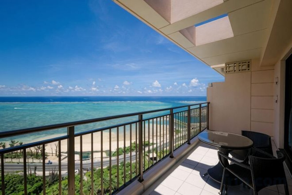 Een balkon met uitzicht op de oceaan, een tafel en stoelen.