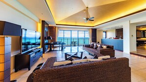 Een ruime woonkamer met een flatscreen televisie, een bank, een bijzettafeltje en een balkon met uitzicht.
