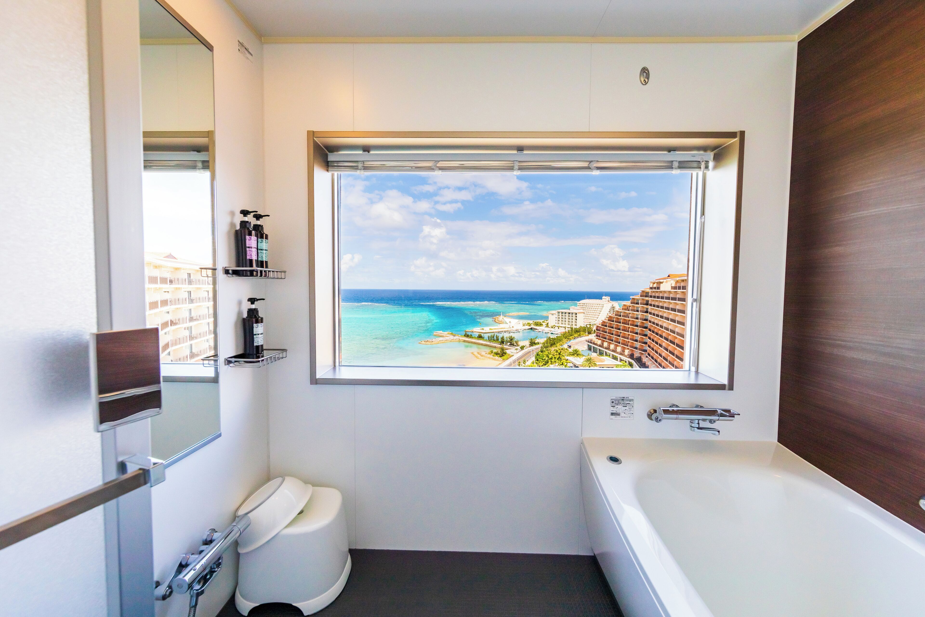 Ein Badezimmer mit großem Fenster und Blick auf Strand und Resort.