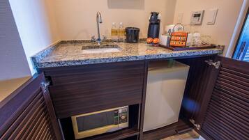 A compact kitchen with a granite countertop, a built-in coffee maker, and a microwave.
