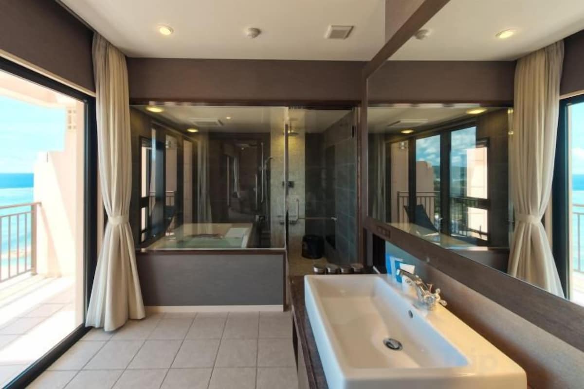 A modern bathroom with a large bathtub, a separate shower area, and a glass-enclosed balcony.