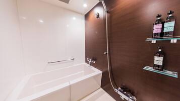 A modern bathroom with a bathtub, a shower, and a glass shelf with toiletries.