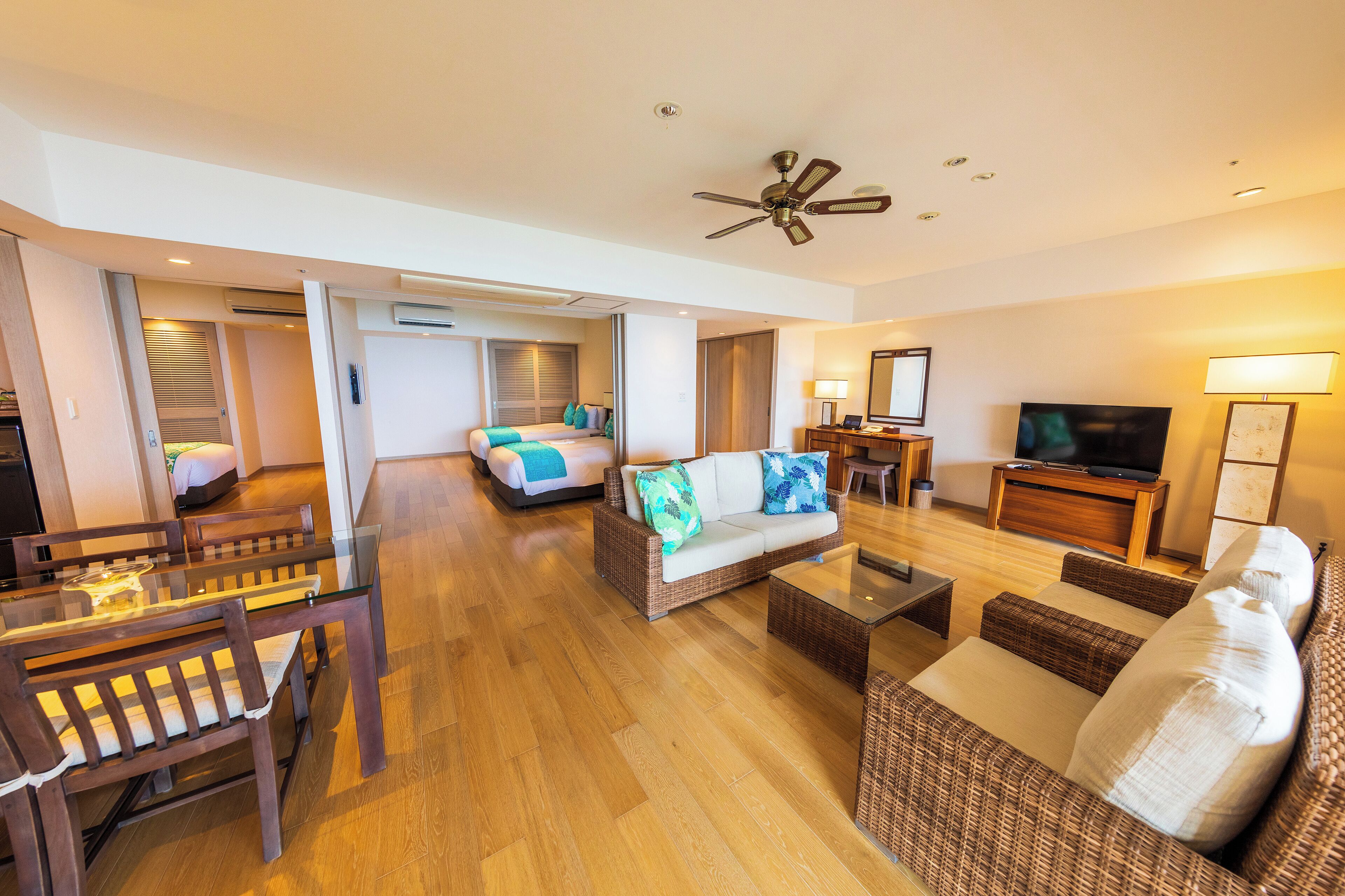 A spacious living area with a sofa, coffee table, TV, and dining set.