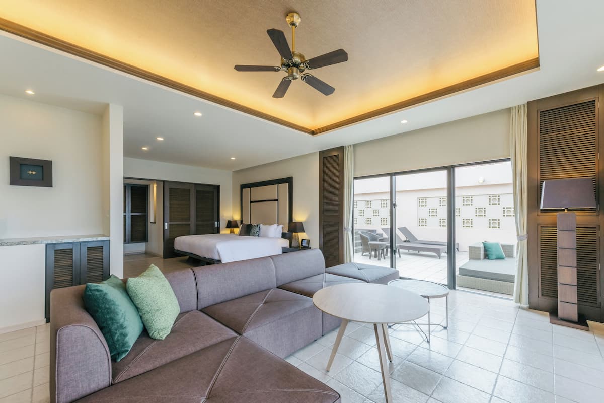 Een moderne hotelkamer met een grote bank, een ronde tafel, een plafondventilator en een groot raam met uitzicht.