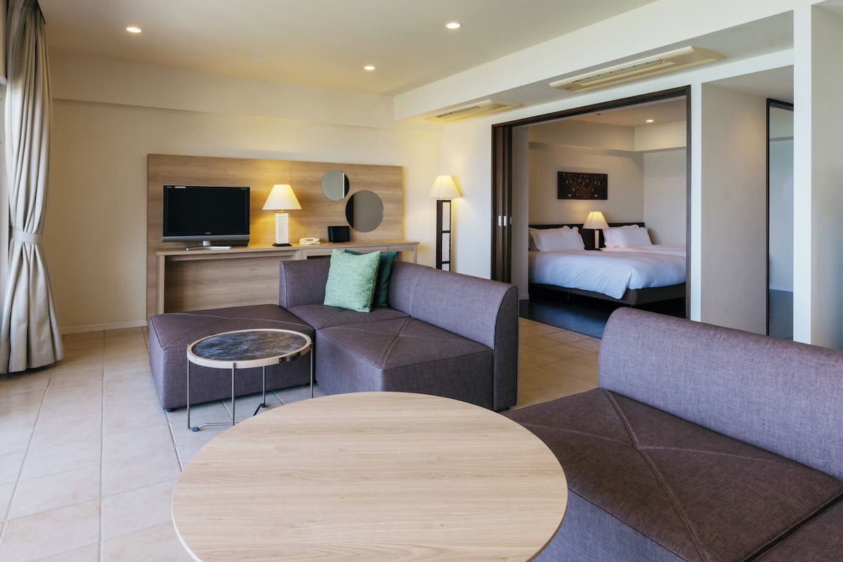 Een moderne hotelkamer met een bank, een ronde tafel, een televisie en een bed.