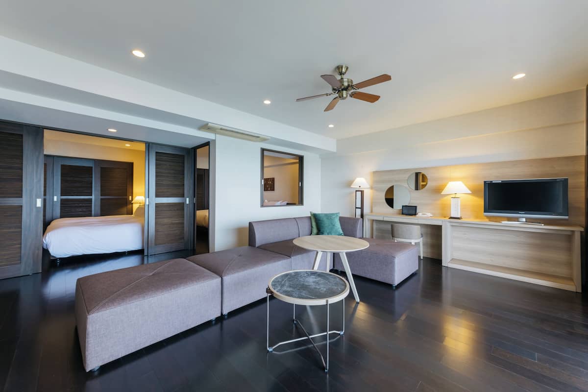 Een moderne hotelkamer met een bank, een ronde tafel, een plafondventilator, een televisie en een bed.