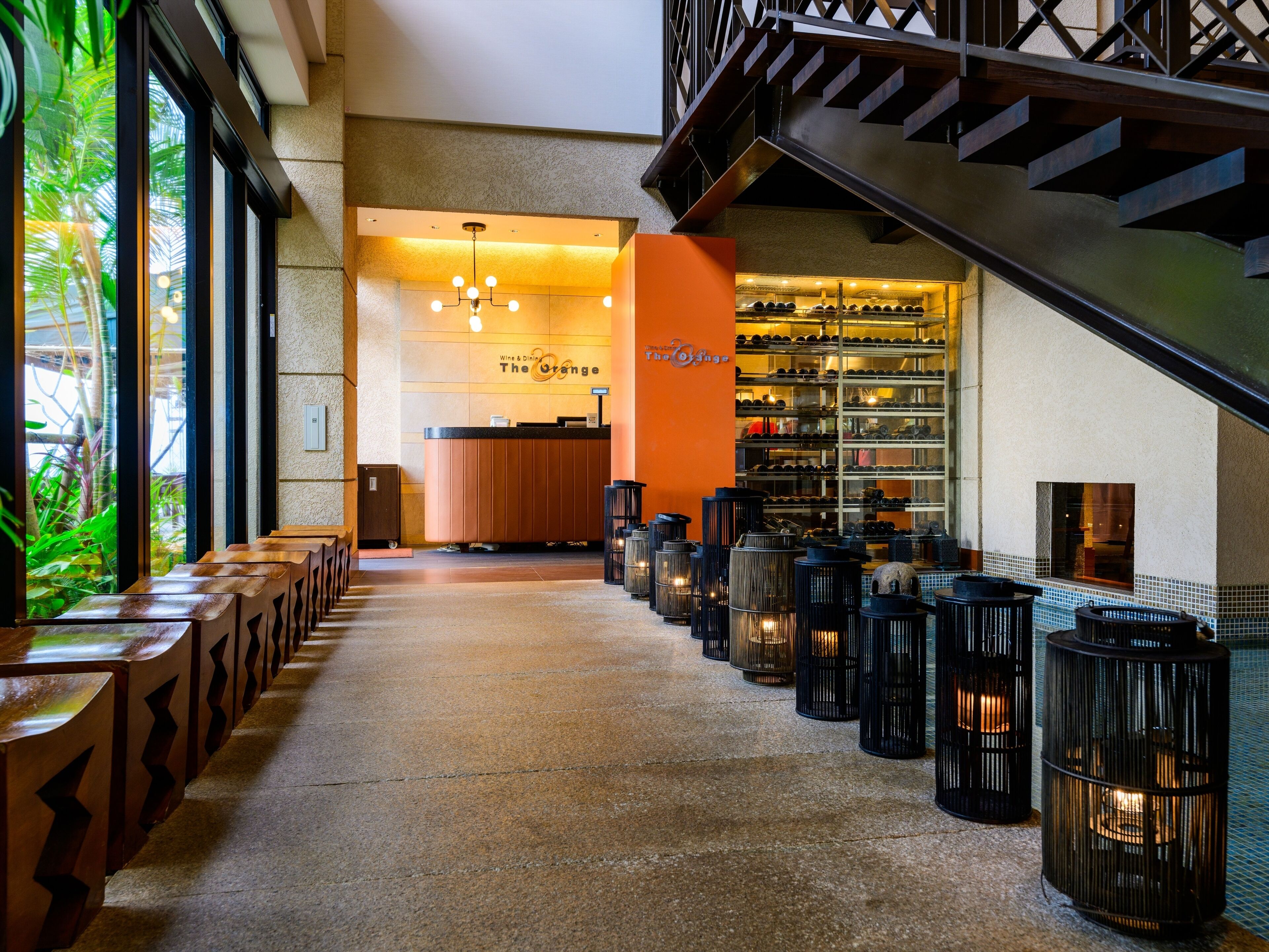 A hotel lobby with a reception desk, a wine and dine section, and a staircase.