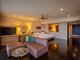 Una habitación de hotel moderna con una cama grande, un sofá, un televisor y un ventilador de techo.