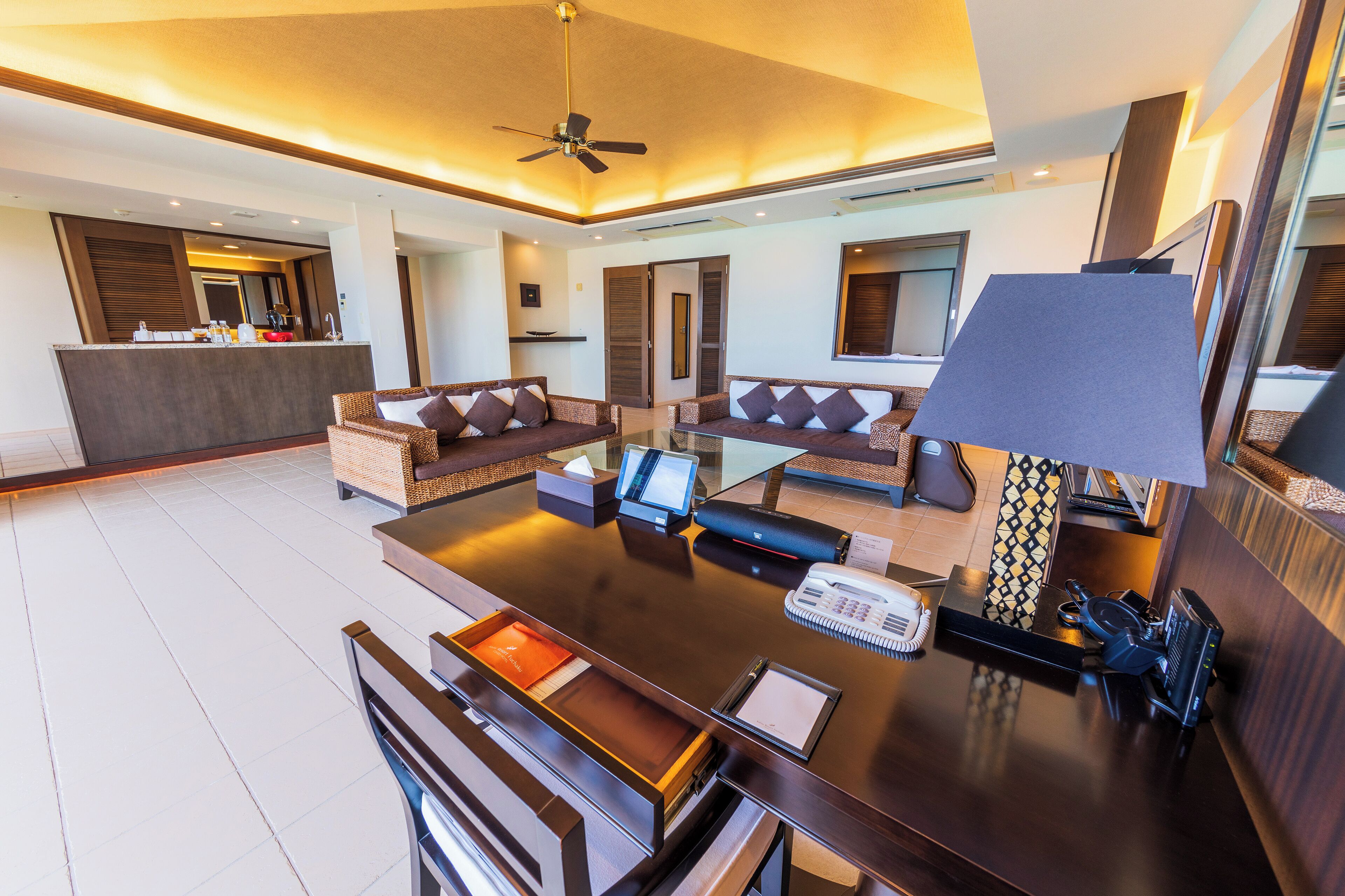Een moderne hotellobby met een receptiebalie, een zithoek en een plafondventilator.