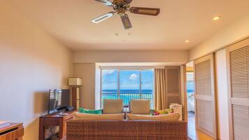 A hotel room with a balcony, a television, a desk, and a bed with pillows.