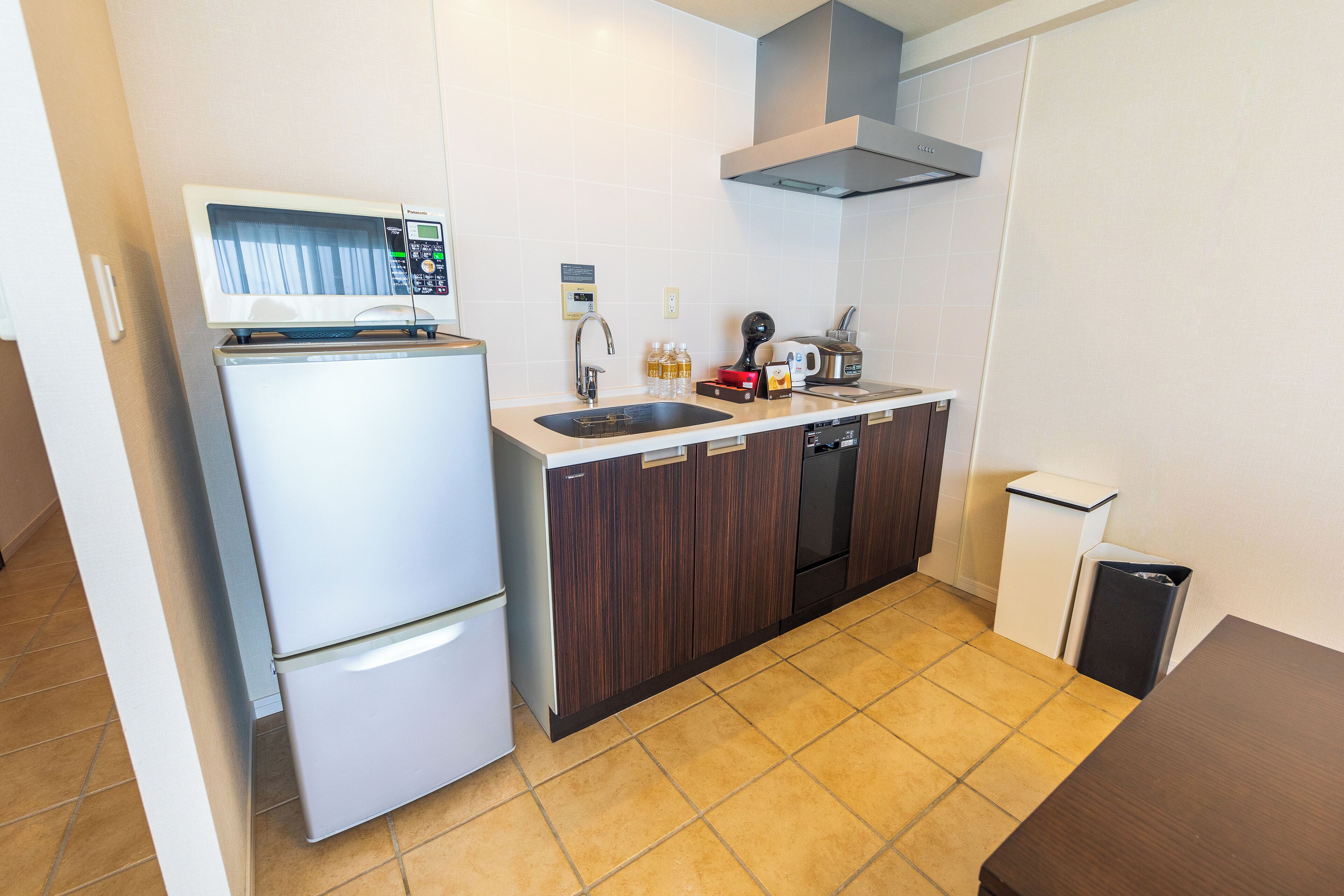A compact kitchen with a refrigerator, microwave, sink, and dishwasher.