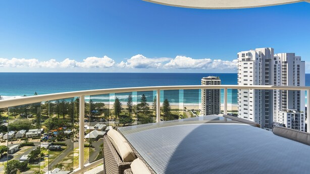 A balcony with a clear view of the ocean and beach, high-rise buildings, and a golf course. - Oscar on Main Resort (Main Beach)