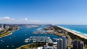 A marina with numerous boats docked, a beach, and high-rise buildings in the background. - Oscar on Main Resort (Main Beach)