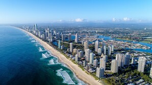 An aerial view of a coastal city with high-rise buildings, a beach, and a river. - Oscar on Main Resort (Main Beach)