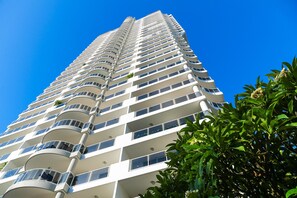Un immeuble de grande hauteur doté de nombreux balcons, avec un ciel bleu dégagé.