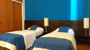 A hotel room with two single beds, each with a blue blanket and pillow, and a wooden headboard. - Alma de Buenos Aires (Buenos Aires)