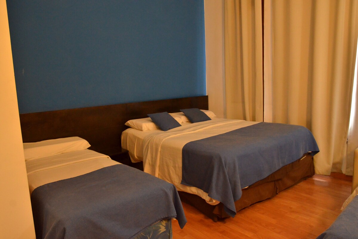 Ein Hotelzimmer mit zwei Betten, Holzboden und blauer Wand.