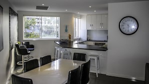 Uma cozinha moderna com armários brancos, uma ilha grande e um espaço de refeições com mesa e cadeiras.