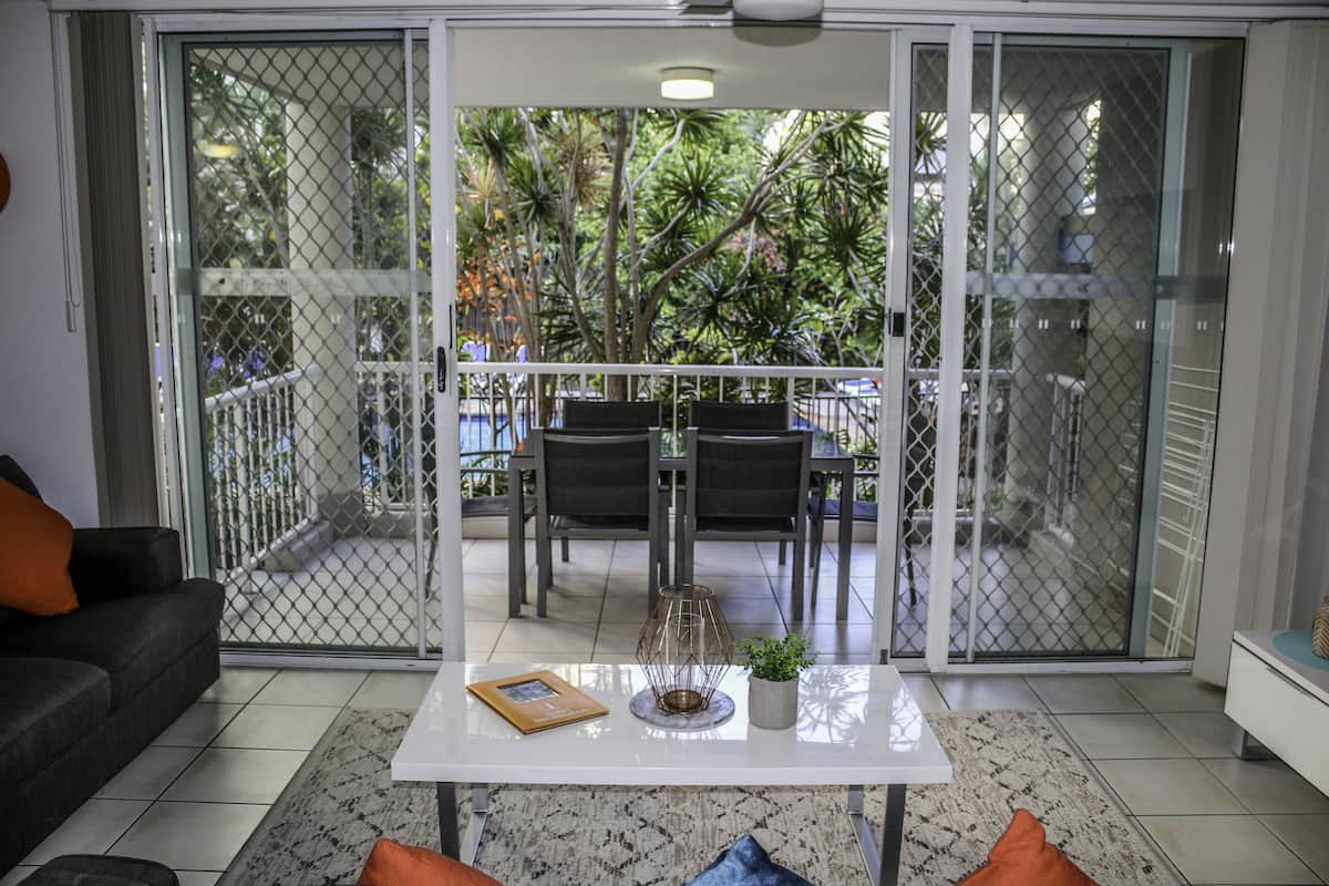 A living room with a white coffee table, a sofa, and a dining area with chairs and a table.