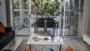 Uma sala de estar com uma mesa de centro branca, um sofá e uma área de jantar com cadeiras e uma mesa.