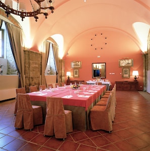 A dining room with a long table set for a meal, surrounded by chairs.