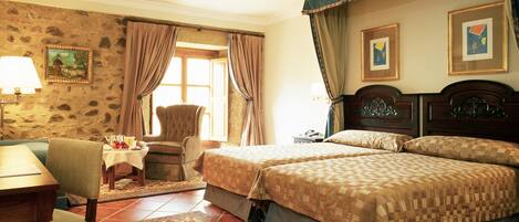 A hotel room with a bed, a chair, a table, and a window.