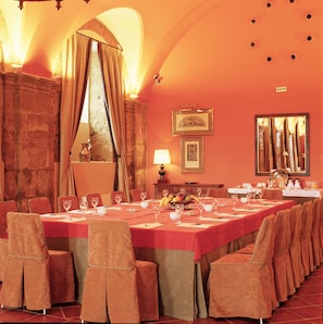 A long dining table with chairs, a chandelier, and a mirror on the wall.