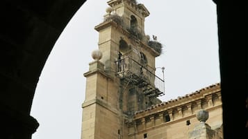 A historic tower with a bell, a balcony, and a weather vane.