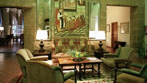 A traditional room with a large tapestry, four armchairs, a wooden coffee table, and a patterned rug. - Parador de Santo Domingo Bernardo de Fresneda (Santo Domingo de la Calzada)