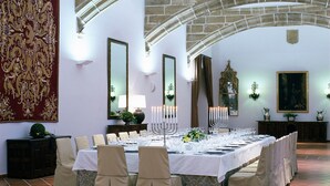 A formal dining room with a long table set for a meal, stone arches, and a large tapestry on the wall. - Parador de Santo Domingo Bernardo de Fresneda (Santo Domingo de la Calzada)