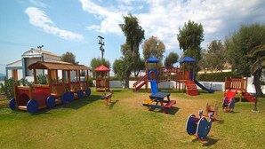 A playground with various play structures including a train ride, swings, and climbing frames. - Lagas Aegean Village (Kos Town)