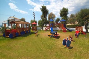 A playground with various play structures including a train ride, swings, and climbing frames. - Lagas Aegean Village (Kos Town)