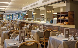 A restaurant with multiple tables set for dining, each with wine glasses and cutlery. - Lagas Aegean Village (Kos Town)