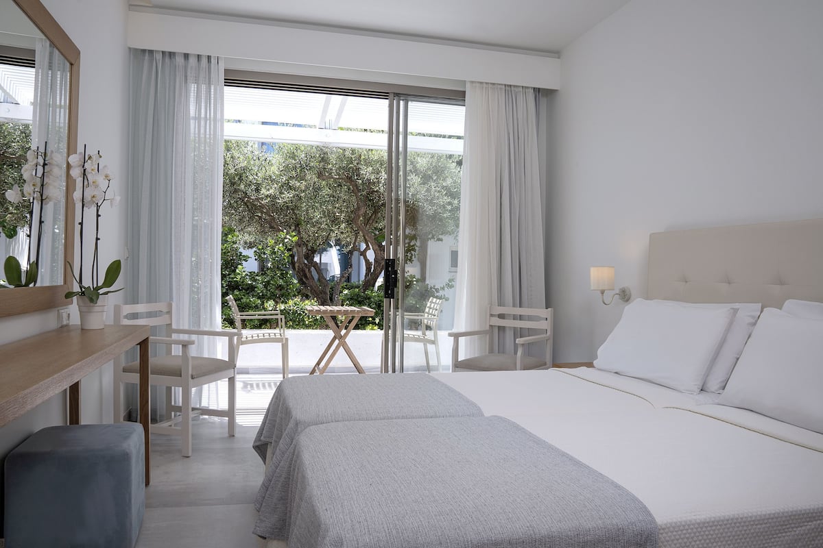 Una habitación de hotel con cama, escritorio, sillas y vistas al exterior.